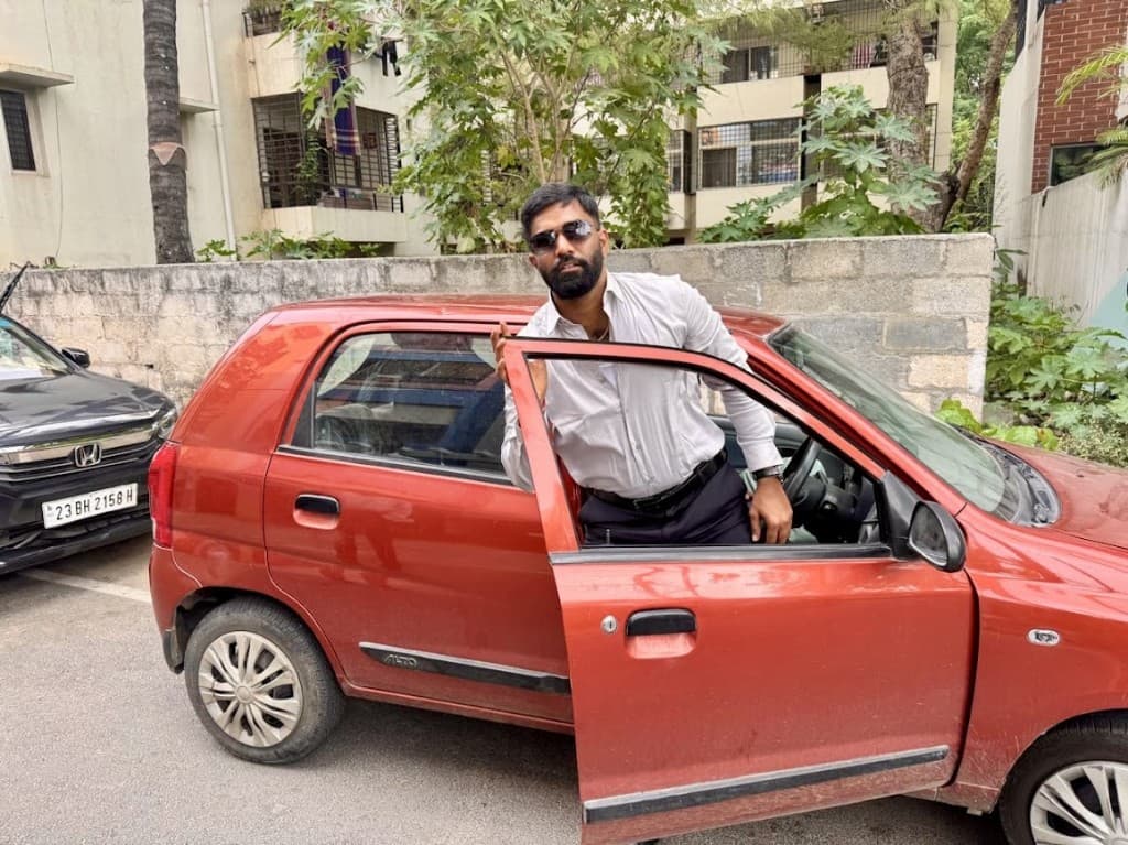 Standing by the open door of the Alto.