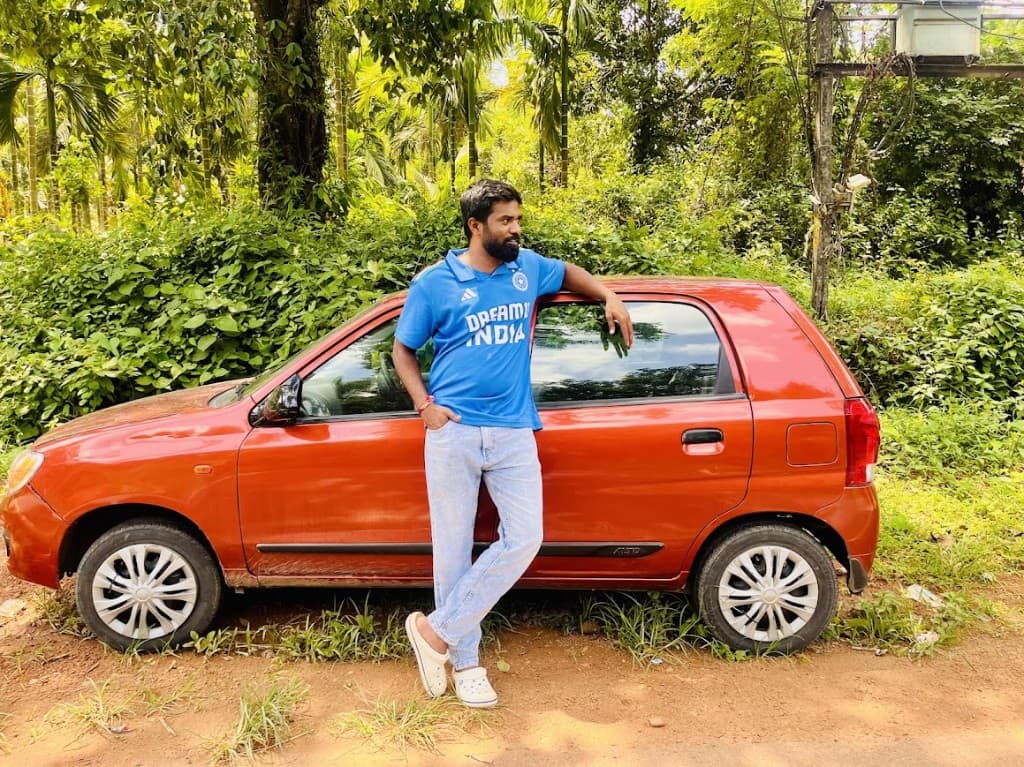 Anand beside the Alto on a forest roadside.